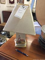 Front and side views of the beach lamp showing the linen shade and wooden base with lighthouse details.