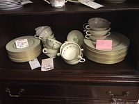 Various Lenox Romance pattern china pieces including plates, soup bowls, and cups displayed on a shelf.