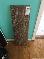 Full view of dark pink marble slab with white streaks leaning against a wall on a wooden floor