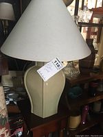 Front view of the tall table lamp with a large beige bulbous ceramic base and cream fabric shade. Shows size and general shape.