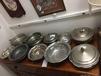 Full view of all pewter bowls and lidded pieces on wooden surface