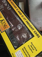 Photo of boxed freight car showing Rail King branding and description of 3 O Scale rounded roof freight cars with operating metal couplers and detailed decorations.