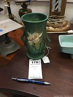 Roseville Magnolia vase on a wooden table next to a pen for scale