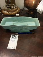 Top and side view of pale green ceramic planter with pen for scale and lot tag.