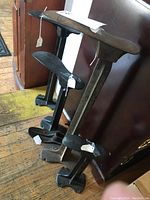 Four heavy metal vintage shoe molds lined up against a wall, showing various sizes and base styles.