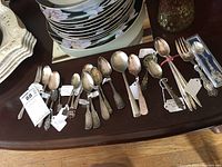 Mixed set of spoons and utensils laid out on a wooden surface, showing variety of sizes and handle styles.