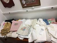 View of assorted napkins and linens spread over a surface showing various colors and some embroidered designs.