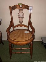 Full view of the antique wooden chair showing carved backrest and re-caned round seat.