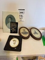 Group photo of five antique portrait photos including tintypes and framed prints on a white surface.