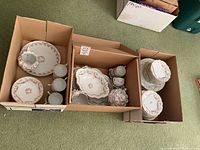 Three cardboard boxes filled with assorted Bridal Rose china including plates, cups, serving bowls.
