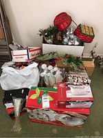 Assorted Christmas decorations including red and silver ornaments, greenery, boxes, and wrapped items.