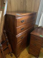 Front view of the wood dresser showing all five drawers and ornate brass handles.