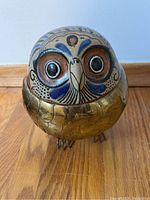 Front view of Mexican owl figurine showing ceramic detailed face and brass body with etched feather scales.