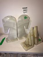 Two sets of stone bookends shown together on a shelf including large horse head carved stone pieces and smaller triangular stone bookends.