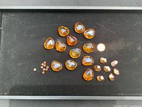 Full set of amber Swarovski crystals on black background with coin for scale