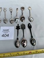 Close-up of eight spoons showing bowl reliefs and finials