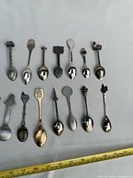 All twenty-two souvenir spoons laid out with ruler for scale