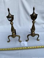 Front view of both brass andirons standing upright