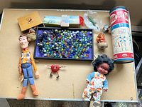 Overall view of lot showing dolls, marbles, Tinkertoy canister, figurines and other items