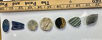 Row of seven assorted cabochons under ruler for scale