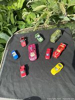 Top view of nine assorted toy cars on black cloth