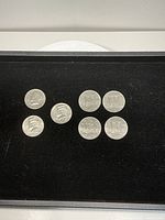 Obverse sides of three US Kennedy half dollars and four Canadian Constitution dollars