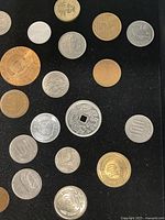 Close view of mixed world coins highlighting square-holed dragon coin, Japanese yen pieces and Edmonton tokens