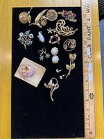 Front view of all jewellery pieces on black board with ruler for scale