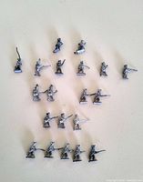 Top-down view of 20 miniature metal soldiers lined in rows on a plain surface, showing their various poses and slight damage.