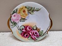 Front view of the antique handpainted floral serving plate showing the detailed rose design and gold handles.