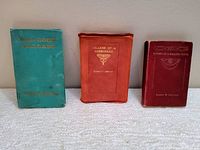 Front view of trio of Robert Service poetry books: turquoise cover 'Bar-Room Ballads', red felt cover 'Ballads of a Cheechako', and burgundy cover 'Rhymes of a Rolling Stone'. All show cover wear.
