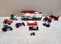 Overview of all vehicles including Hess fire truck and assorted small tractors, motorcycles, classic cars, and plastic vehicles arranged on carpet