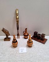 Assortment of six vintage hand-carved wooden decor items including figurative bust, large fork with figure handle, small decorative pitchers, and salt and pepper set.