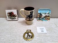 Four vintage hunting themed items: matchbox holder, mug, rectangular tray, and brass horse brass.