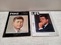 Photo of two magazines with covers featuring portraits of John F. Kennedy, one by Saturday Evening Post with illustrated cover, and one by Life magazine with photographic cover.