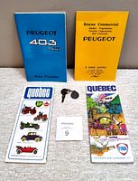 Overall lot showing two Peugeot 1966 car booklets, original Peugeot car key with brass medallion key ring, and two vintage 1973-74 Quebec maps advertising BP and Fina gas/oil companies.