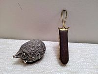 Photo of handcarved soapstone hedgehog brush alongside a second vintage brush with wooden handle and gold metal top.