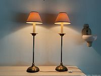 Pair of lamps lit on white mantel, showing overall height, style and finish