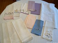 Overview of tablecloth and assortment of embroidered linen hand towels showing different colors and embroidery styles.