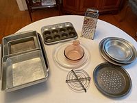 Photo showing all items including aluminum pie plates, cake pans, muffin tins, grater, glass pie plate, round roasting pans, and a round pan with holes.