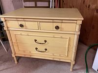 Front view showing two small upper drawers and two larger lower drawers with faux bamboo trim and metal hardware