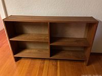 Front view of the wooden bookcase showing two compartments and one adjustable shelf on the left.