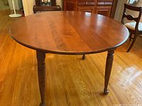 Solid wood round dining table 44 inch diameter with turned legs in a medium brown finish, showing the top surface and legs.