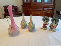 Photo showing all five items: two hand-painted Ukrainian vases, pink hand-blown pitcher, and two china figurines.