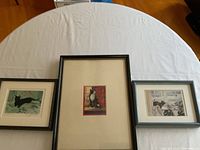 Overview of three framed cat prints laid on a round white table.