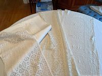 Photo showing three fine lace table runners with different lace patterns and the linen tablecloth underneath on a table.