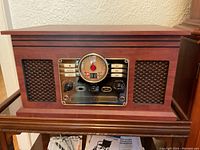Front view of the MET compact music system showing the retro style wooden cabinet, speaker grilles, dial and controls.