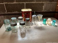 Full lot of vintage jars, cookie tin, toddy mixer and glass insulators on table