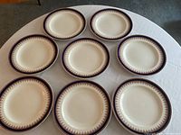Eight matching Royal Worcester vitreous dinner plates arranged on a white tablecloth; shows overall set.
