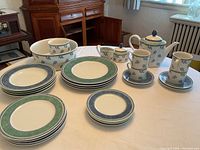 Full overview of dinnerware set showing plates, bowls, mugs, coffee pot, creamer and sugar bowl
